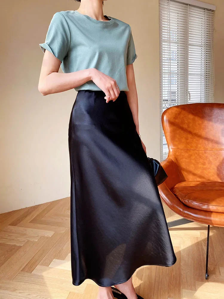 Women’s elegant skirt worn with a crossbody bag and heels.