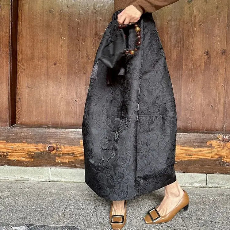 Model walking in a garden wearing a patterned loose skirt.
