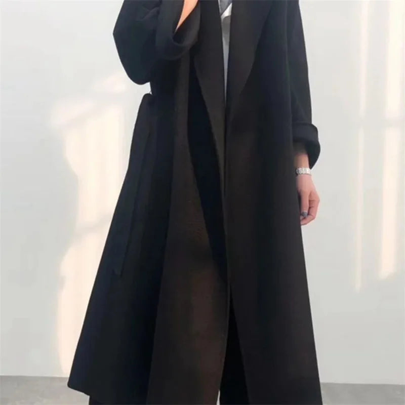 Side profile of a long loose wool coat in black.