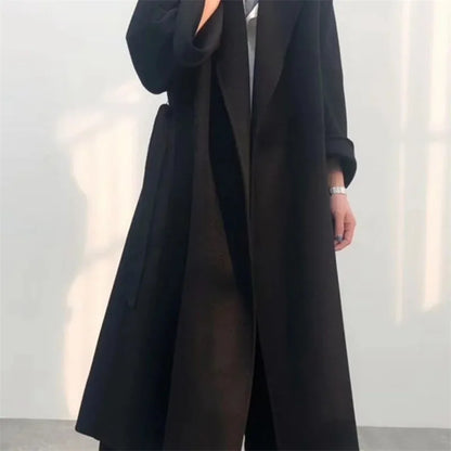 Side profile of a long loose wool coat in black.